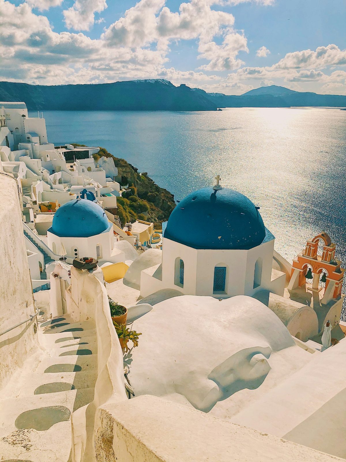 Whitewashed houses and blue domes above the Santorini caldera at golden hour